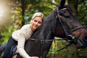 Frau umarmt glückliches Pferd nach Lockerungsübungen mit dem Pferd